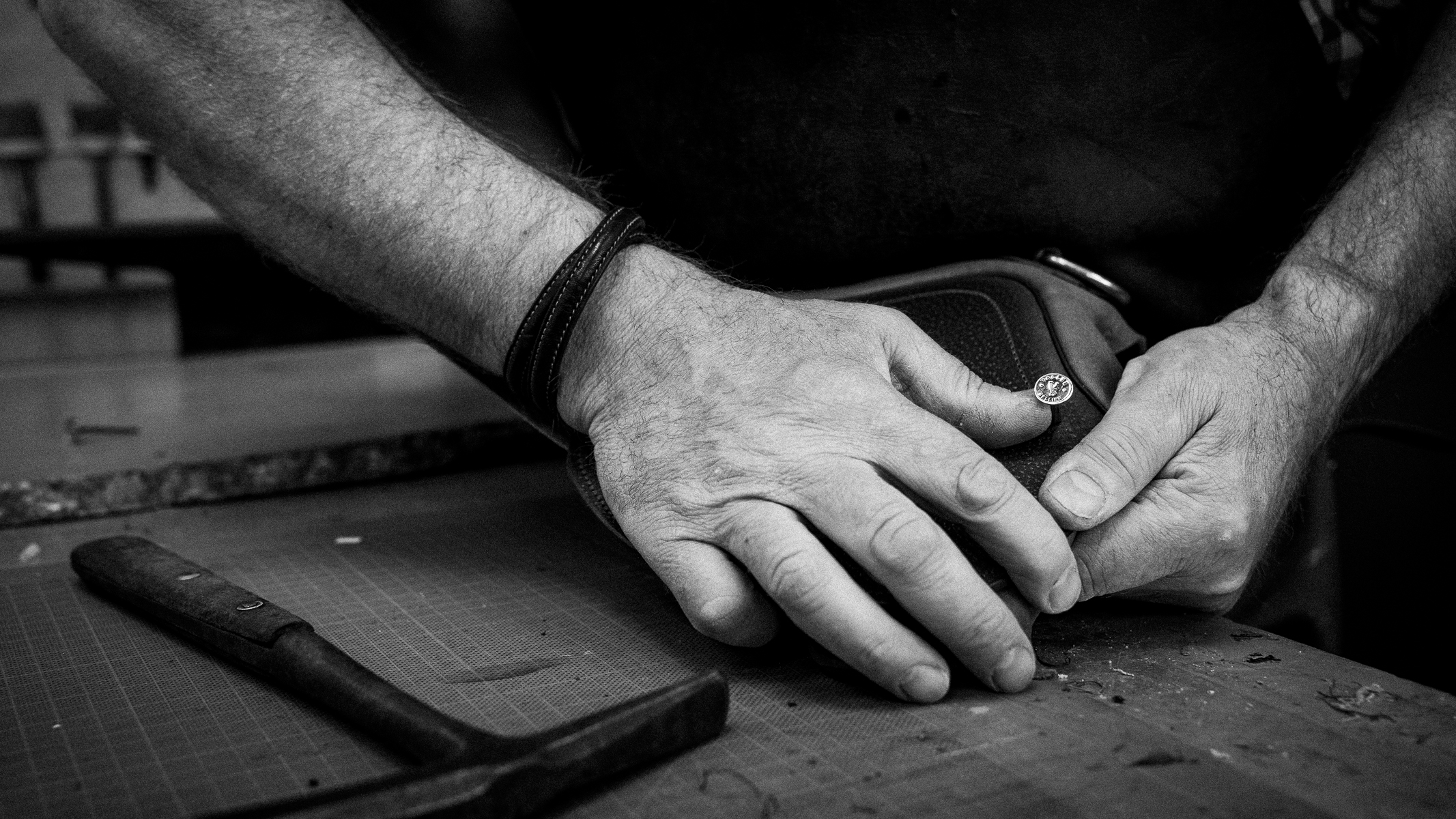 Mains d'artisan sellier travaillant le cuir à l'atelier Vallée-Sellier en Normandie
